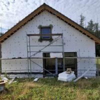 Rodinný dům ve fázi výstavby s nainstalovaným polystyrenovým zateplením a postaveným lešením