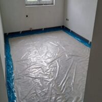 Místnost ve výstavbě s plastovou fólií rozprostřenou na podlaze, připravená pro další stavební práce