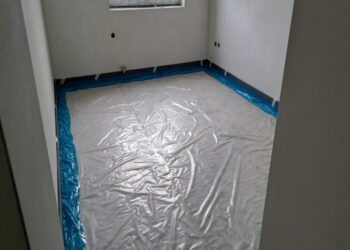 Místnost ve výstavbě s plastovou fólií rozprostřenou na podlaze, připravená pro další stavební práce